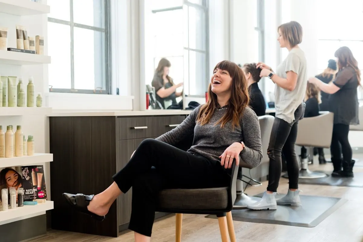 A beauty professional laughing in a bright modern hair salon