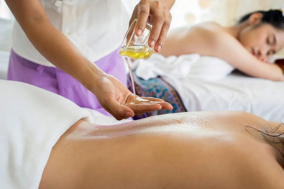 Massage therapist preparing warm oil for a treatment